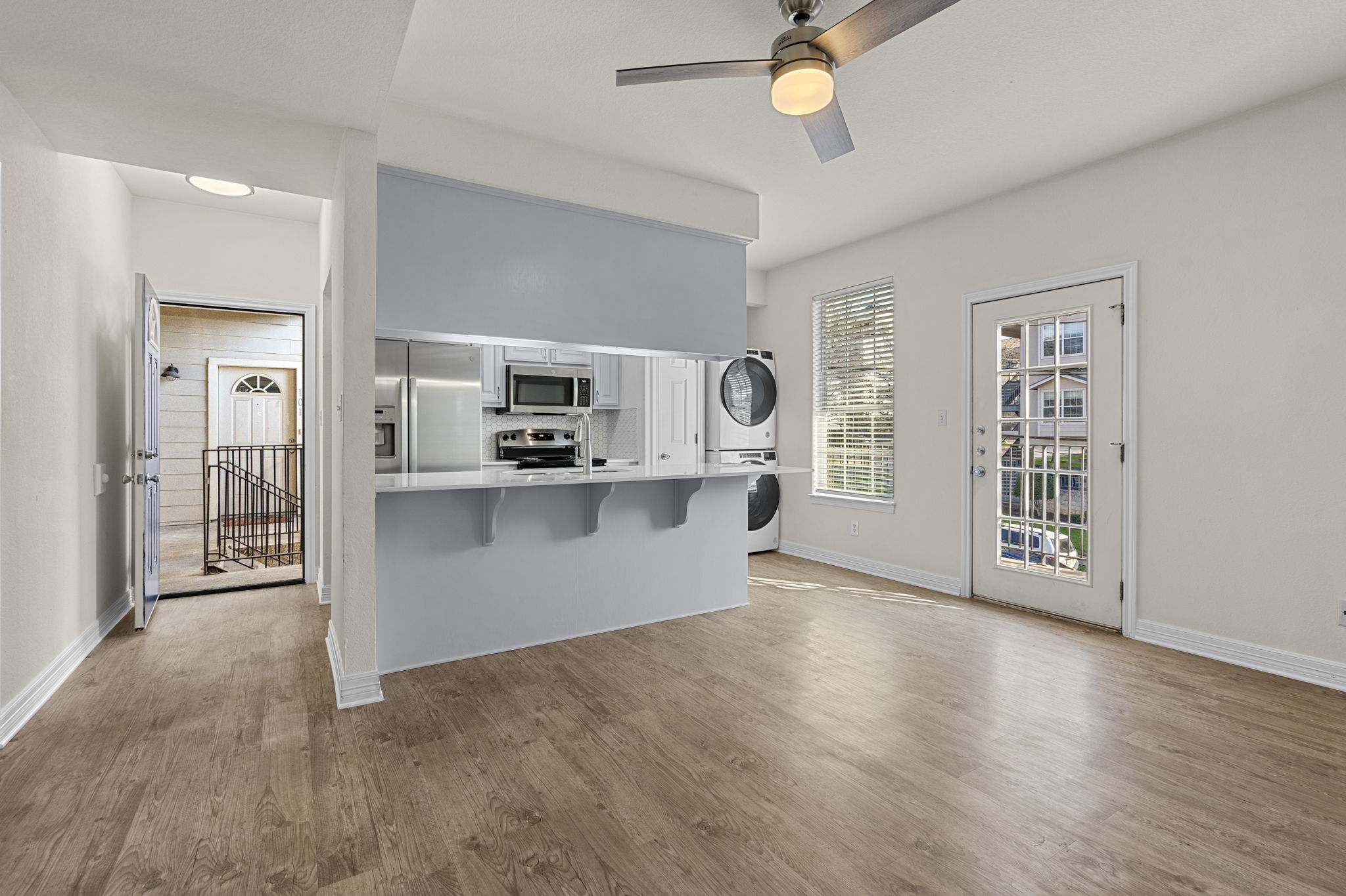 Renovated open-plan living room and kitchen with quartz countertops — student apartment at Whitestone West Campus, Austin TX